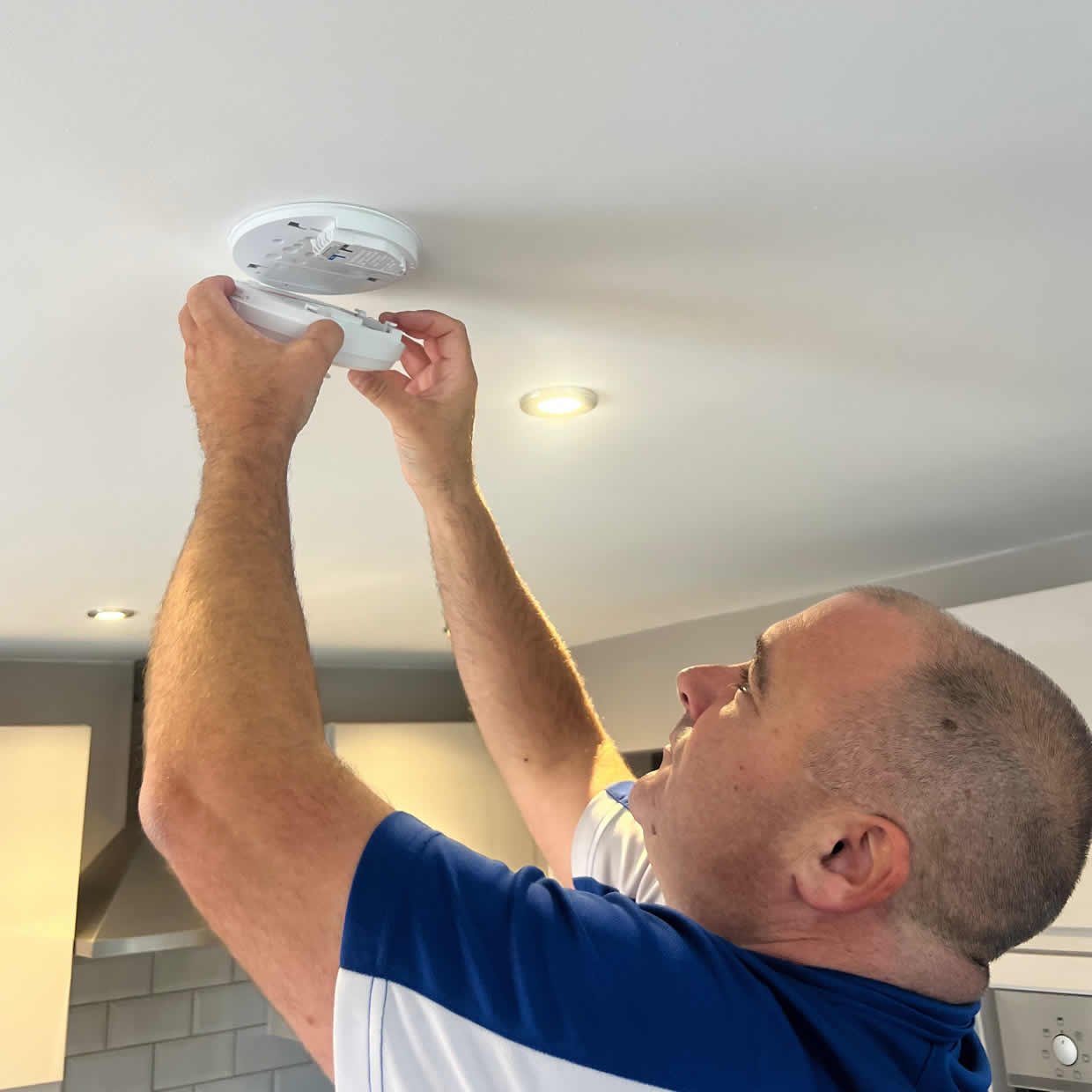 Smoke alarm installer fitting an alarm in a Bangor property